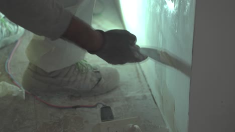 Close-up-shot-of-male-worker-putting-plaster-on-the-wall-with-a-spatula