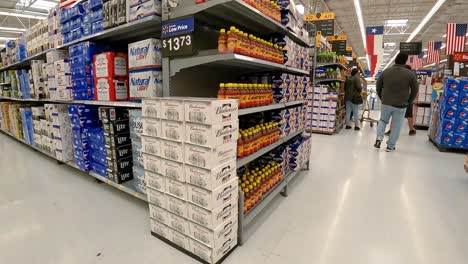 Slowly-passing-cases-of-beer-bottles-and-cans-stacked-on-shelves-in-an-American-mega-grocery-store