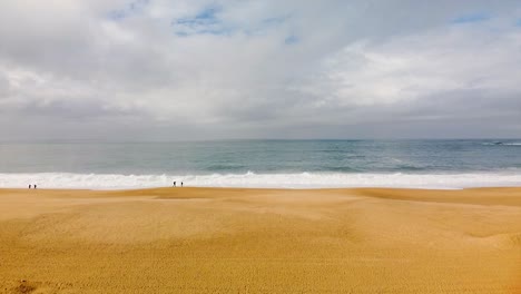 Establisher-aerial-of-vast-shoreline-in-Nazarè,-Portugal,-large-waves-crashing