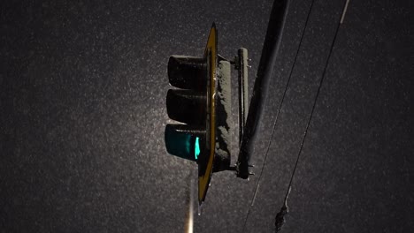 Backlit-streetlight-changes-from-green-to-yellow-as-snow-falls-in-slow-motion