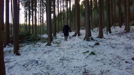 Man-in-winter-clothes-with-a-backpack-walks-through-a-snowy-forest-off-the-road