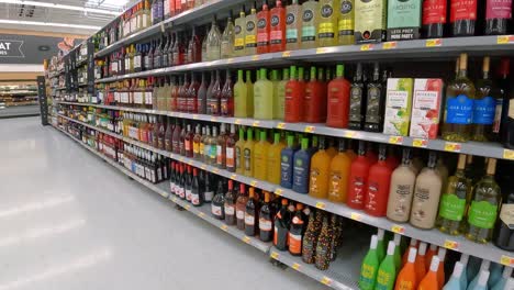 Pasando-Lentamente-Botellas-De-Vino-Y-Mezcladores-En-Estantes-En-Una-Mega-Tienda-De-Comestibles-Americana