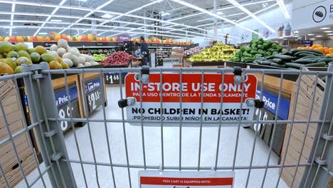 POV---Pushing-an-emptying-grocery-cart-through-the-displays-of-fresh-produce-in-a-Walmart