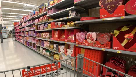 Punto-De-Vista:-Empujar-Un-Carrito-De-Supermercado-Más-Allá-De-Las-Exhibiciones-De-Dulces-De-San-Valentín-En-Una-Tienda-De-Comestibles-Estadounidense