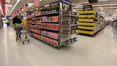 Customers-walking-past-displays-of-food,-snacks-and-clothing-in-an-American-mega-market