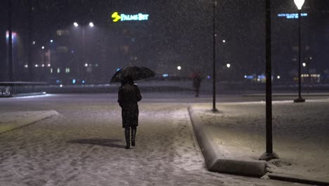 Mujer-Vestida-De-Negro-Sosteniendo-Un-Paraguas-Se-Aleja-Mientras-Cae-La-Nieve