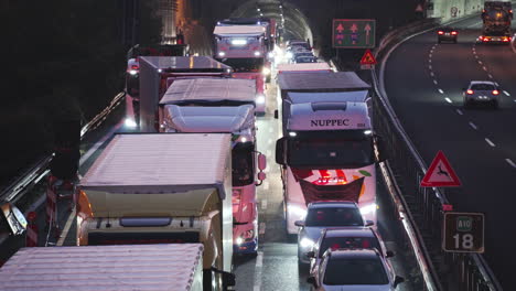Trucks-and-cars-stuck-in-heavy-traffic-jam,-driving-slowly-at-night