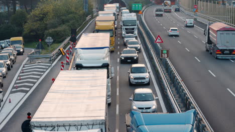 Front-view-of-heavy-traffic-road-seen-from-overpass-bridge,-trucks-and-cars