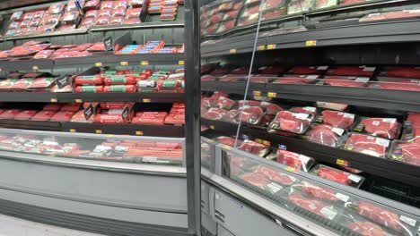 Empujando-Un-Carrito-De-Supermercado-Más-Allá-De-Las-Exhibiciones-Refrigeradas-De-Carne-De-Res-Y-Cerdo-En-Una-Mega-Tienda-De-Comestibles-Americana