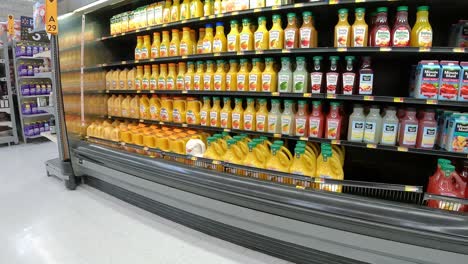 Pasando-Lentamente-Las-Exhibiciones-Refrigeradas-De-Jugo-De-Frutas-Y-Limonada-En-Una-Mega-Tienda-De-Comestibles-Americana