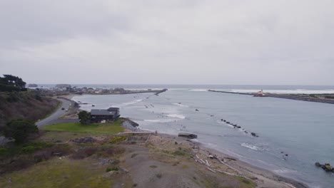 Sweeping-aerial-view-of-cloudy-PNW-coast,-Coquille-river,-rockwall-jetty-and-ocean