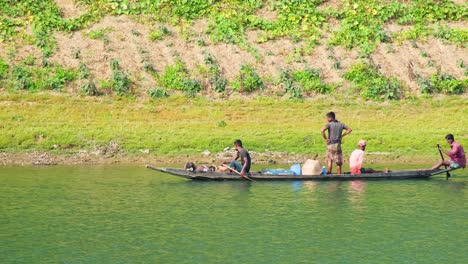 Fishermen-laboriously-row-wooden-boats-on-the-Surma-River-in-Sylhet,-Bangladesh,-showcasing-the-hardworking-life-of-river-workers