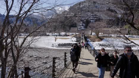 Tourists-Crossing-Rope-Bridge-to-Shirakawago-in-Winter-Mountain-Scene