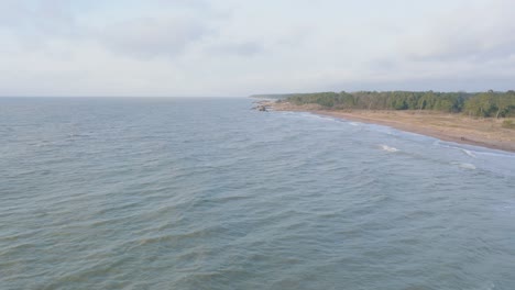 Aerial-establishing-view-of-Port-of-Liepaja-concrete-pier,-Baltic-sea-coastline-day,-big-waves-splashing,-slow-motion-drone-shot-moving-backward