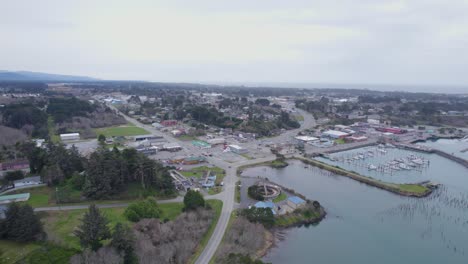 Slow-descending-aerial-over-coastal-town,-road,-and-harbor-of-Bandon-Oregon