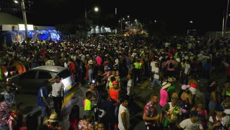 Calles-Llenas-De-Gente-Celebrando-El-Carnaval-De-Barranquilla,-De-Noche-En-Colombia---Reversa,-Tiro-Con-Drones