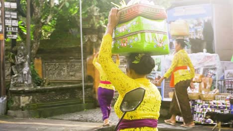 Woman-in-traditional-Balinese-colorful-dress-carry-baskets-of-food-on-head-to-temple