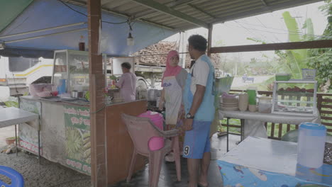 Southeast-asian-man-stands-and-orders-food-at-restaurant-on-Thai-Malay-border