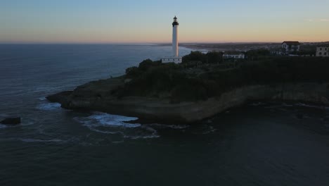 Drone-flying-towards-Biarritz-lighthouse-at-sunset,-France