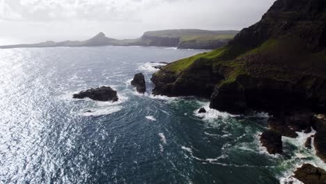 Waves-Crashing-Up-Against-Mossy-Green-Coastal-Cliffside,-Isle-Of-Skye,-Scotland