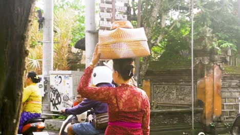 Women-in-traditional-red-Balinese-dress-carries-food-to-temple-pass-busy-road