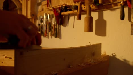Close-up-of-the-hands-of-a-person-manually-sanding-a-wooden-board-at-sunset-time