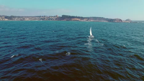 Cinematic-rotating-shot-of-a-small-sailboat-sailing-off-the-coast-of-Algarrobo,-Chile