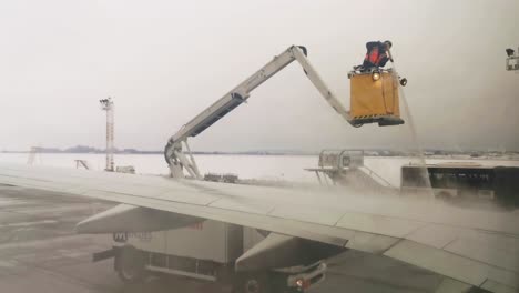 Airport-crew-member-spraying-an-airplane-wing-to-remove-the-ice-during-a-winter-storm