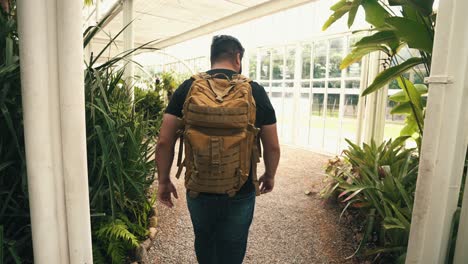 Handheld-shot-of-young-male-traveler-with-backpack-walking-through-a-brasilian-tropical-greenhouse