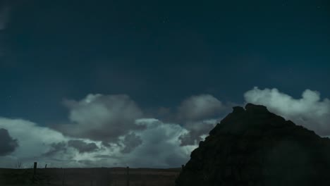 Timelapse-of-clouds-rolling-past-on-a-moonlit-night-with-a-peat-stack-in-the-foreground