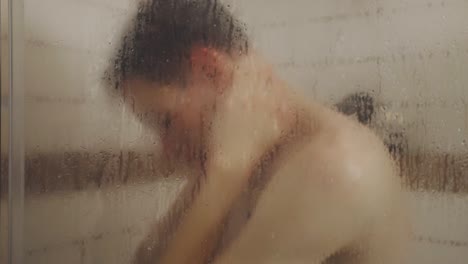 Portrait-Of-A-Man-Behind-Glass-Shower-Cabin-Taking-A-Bath