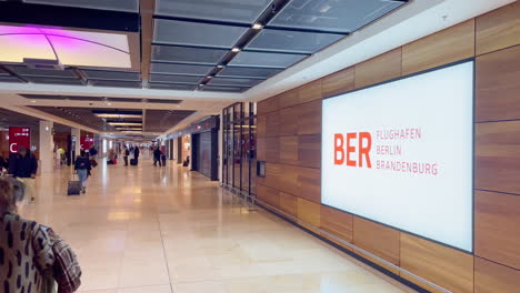 Berlin-Brandenburg-Airport-Terminal-with-Sign-and-Passengers-at-Gate