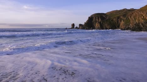 Golden-hour-shot-of-some-waves,-the-beach-and-the-headland-around-Dalmore-beach-near-Carloway
