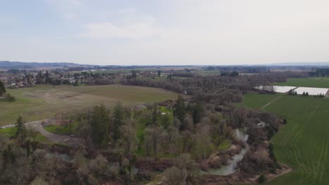 Rising-aerial-over-river-water-and-trees-surrounded-by-crop-fields-and-farm