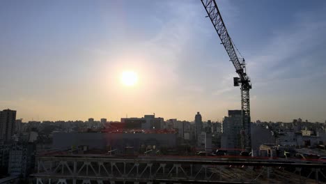 Aerial-view-of-swinging-construction-crane-at-site-against-vibrant-sunset-sky