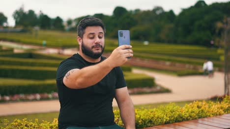 White-bearded-young-man-with-black-shirt-talking-to-the-cell-phone-on-a-mobile-phone-online-tourist-on-a-video-call-in-slow-motion