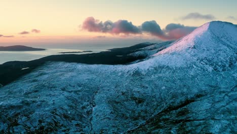 Timelapse-drone-shot-of-clouds-rolling-over-a-snow-topped-Clisham-mountain,-the-tallest-mountain-on-the-Isle-of-Harris,-part-of-the-Outer-Hebrides-of-Scotland