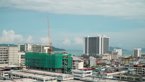 Die-Skyline-Von-Kota-Kinabalu-Zoomt-An-Einem-Sonnigen-Tag-Zur-Baustelle-Eines-Mehrfamilienhauses-Mit-Einem-Kran-An-Der-Spitze