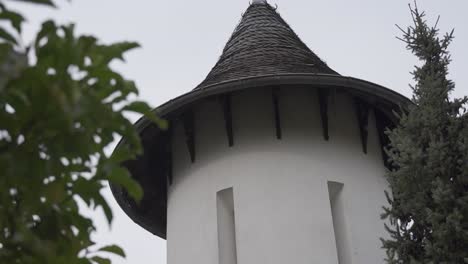 Kleiner-Weißer-Turm-Mit-Spitzem-Dach-Und-Länglichen-Fenstern-Zwischen-Bäumen