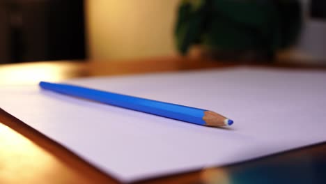 Blauer-Buntstift-Wird-Auf-Ein-Blatt-Papier-Auf-Ihrem-Schreibtisch-Gelegt-Und-Wieder-Weggenommen