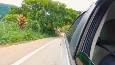 Looking-back-following-car-traffic-on-a-rural-road-in-Brazil,-Rear-view-from-the-car's-side-window