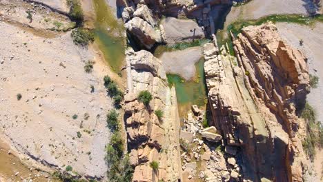 Drohnenaufnahme-Einer-Schlucht-Und-Des-Wasserfalls-Zwischen-Wüstenbergen-In-Bousaada,-Algerien