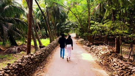 Schönes-Paar,-Das-Auf-Beiden-Seiten-Von-Palmen-Abseits-Der-Straße-Läuft,-Urlaubskonzepte-Des-Paares,-Wunderschönes-Palmenwaldgebiet-Und-Kamera,-Die-Das-Paar-Verfolgt