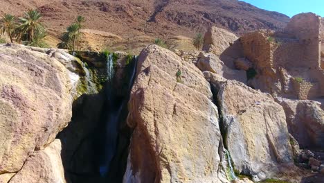 Drohnenaufnahme-Eines-Wunderschönen-Wasserfalls-Zwischen-Wüstenbergen-In-Bousaada,-Algerien