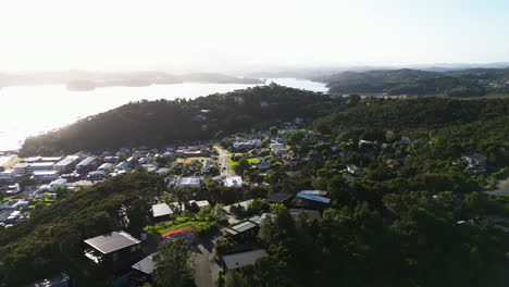 drone-revealing-the-bay-of-islands-pahia-town-in-New-Zealand-with-stunning-sunshine-over-the-coastline-during-a-summer-day-of-summer-travel-holiday-destination