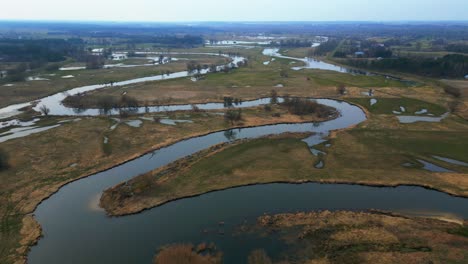 Spring-aerial-view-of-flooded-fields-and-meandering-river-in-the-countryside-on-a-sunny-day