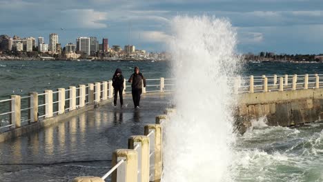 A-middle-aged-Turkish-couple-is-running-away-from-waves-on-the-Historical-Moda-Pier-in-Istanbul-in-slow-motion