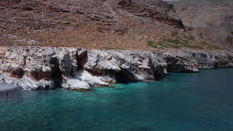 Luftaufnahme-Von-Menschen,-Die-Im-Türkisfarbenen-Wasser-Zu-Den-Höhlen-Des-Marmara-Strandes-Schwimmen