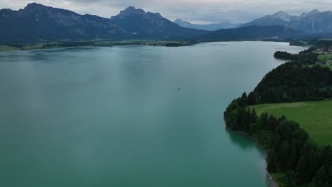 Turquoise-water,-flying-over-the-Forggensee-in-summer,-a-popular-travel-location-in-southern-Bavaria
