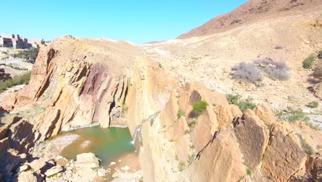 drone-shot-of-a-beautiful-waterfall-between-desert-mountains-in-bousaada-algeria-Sahara